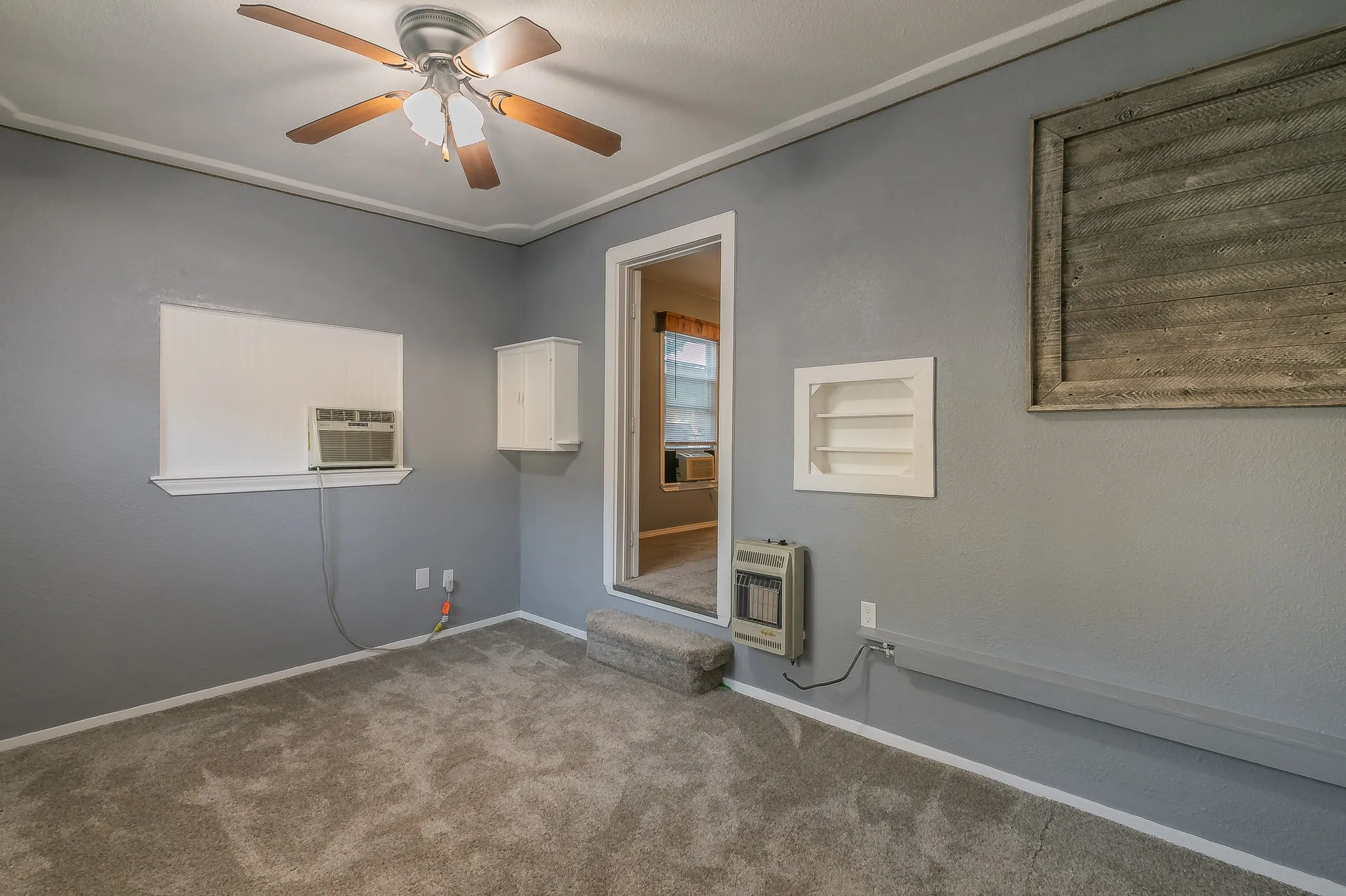 Carpeted spare room featuring heating unit, ceiling fan, and cooling unit