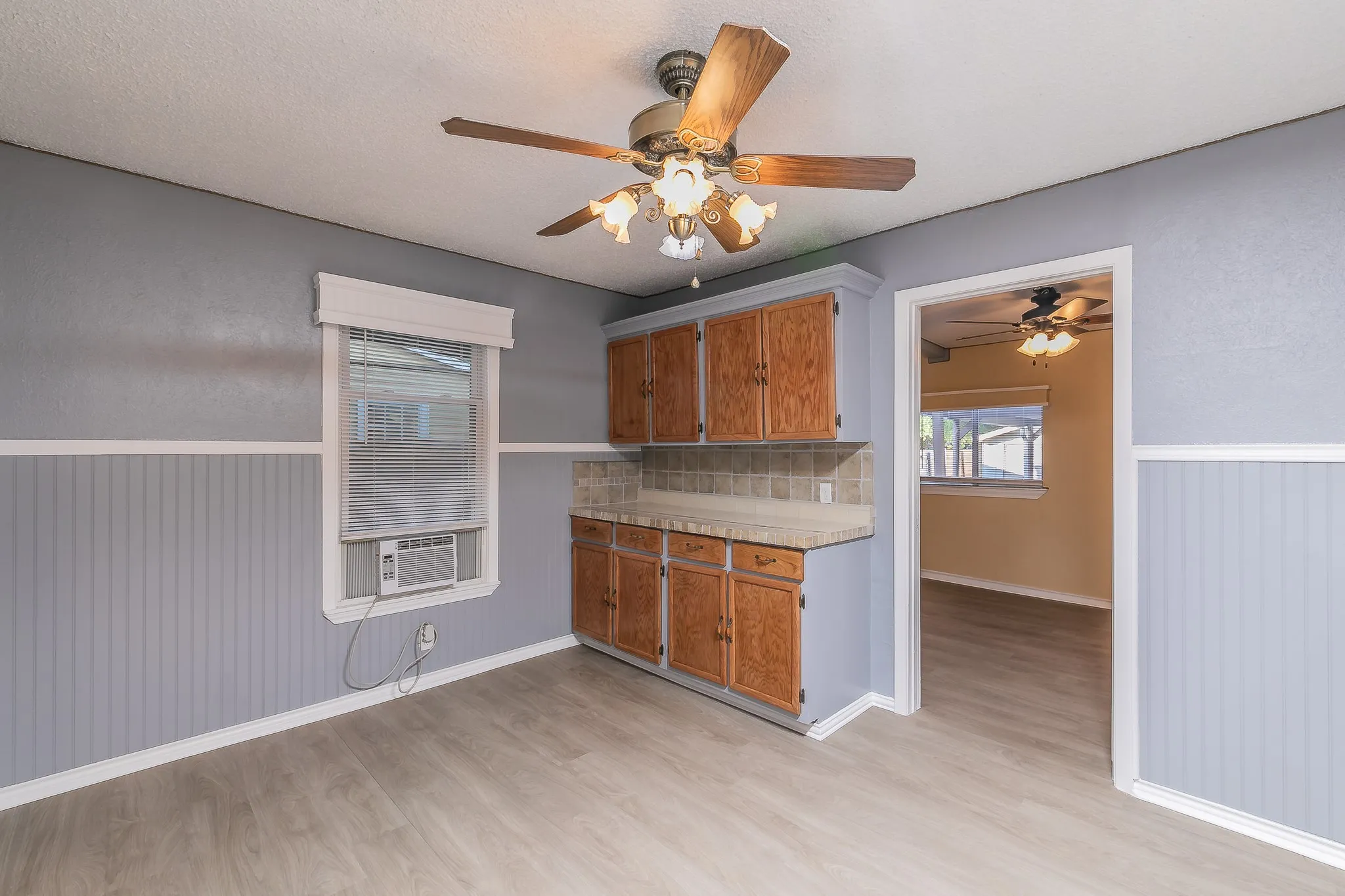Kitchen with backsplash, cooling unit, wooden walls, ceiling fan, and light wood-type flooring