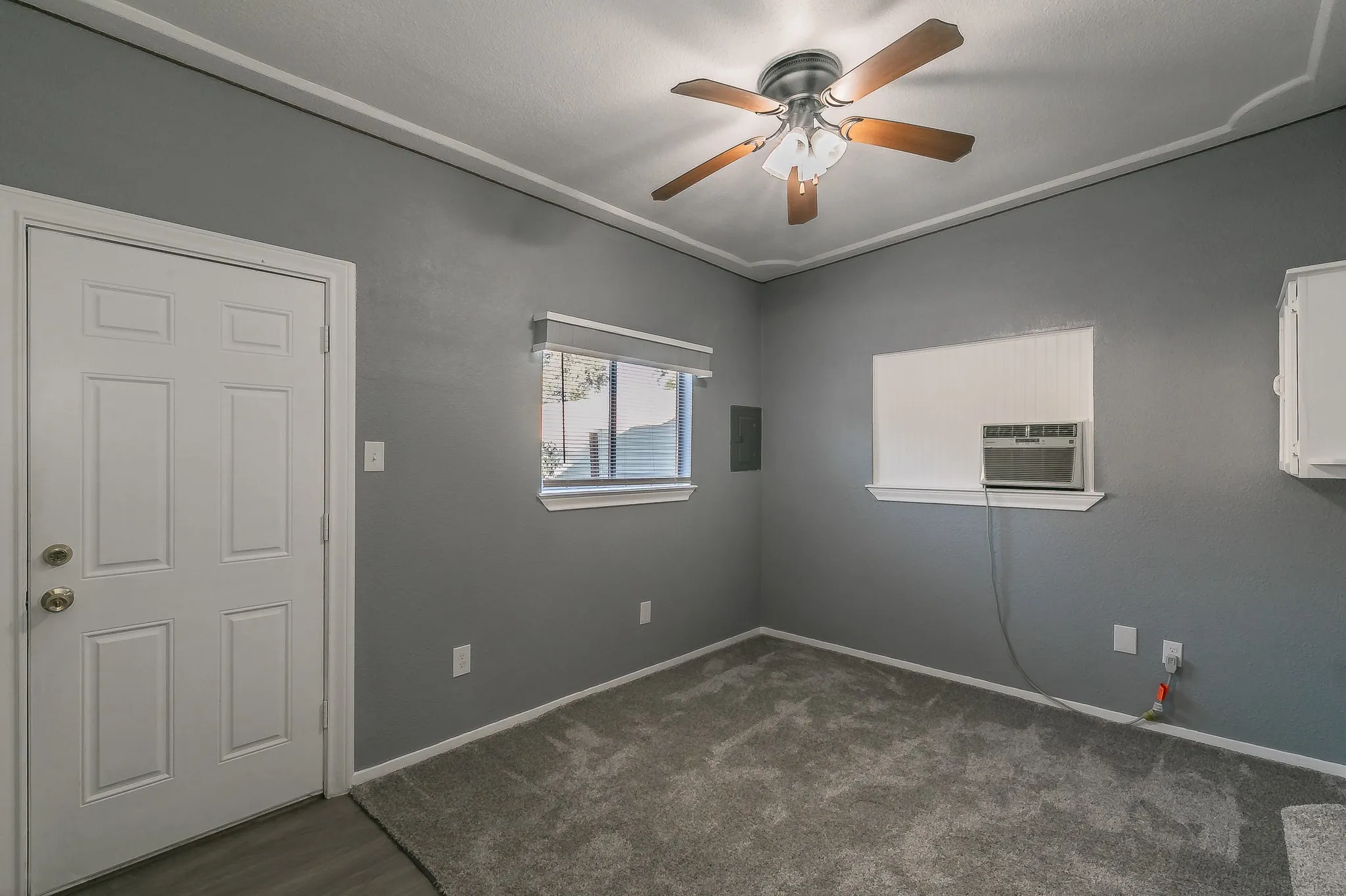 Spare room featuring dark colored carpet, ceiling fan, and cooling unit