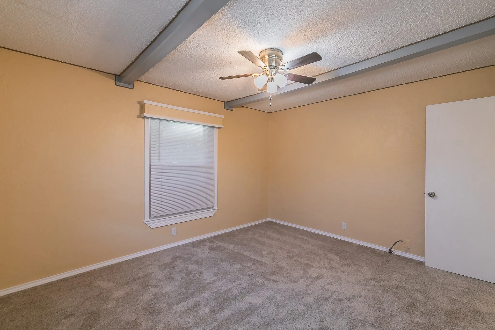 Unfurnished room with beamed ceiling, carpet, a textured ceiling, and ceiling fan