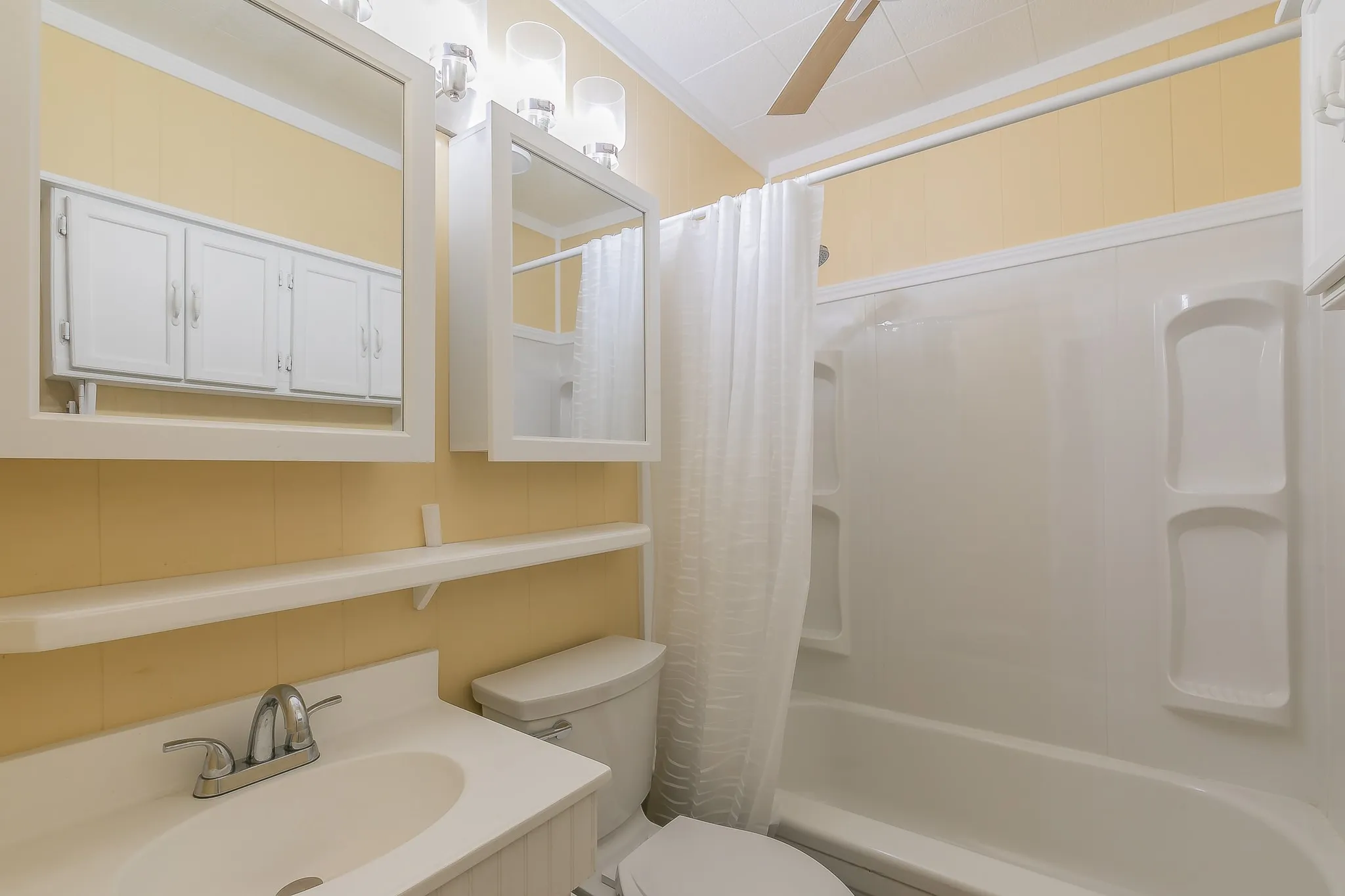 Full bathroom featuring vanity, crown molding, ceiling fan, toilet, and shower / tub combo