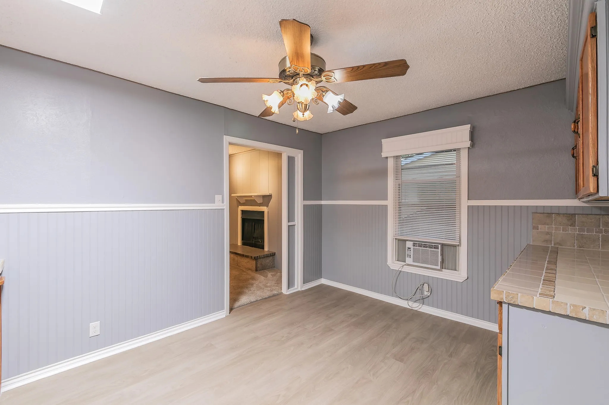 Unfurnished dining area with a textured ceiling, light wood-type flooring, cooling unit, and ceiling fan