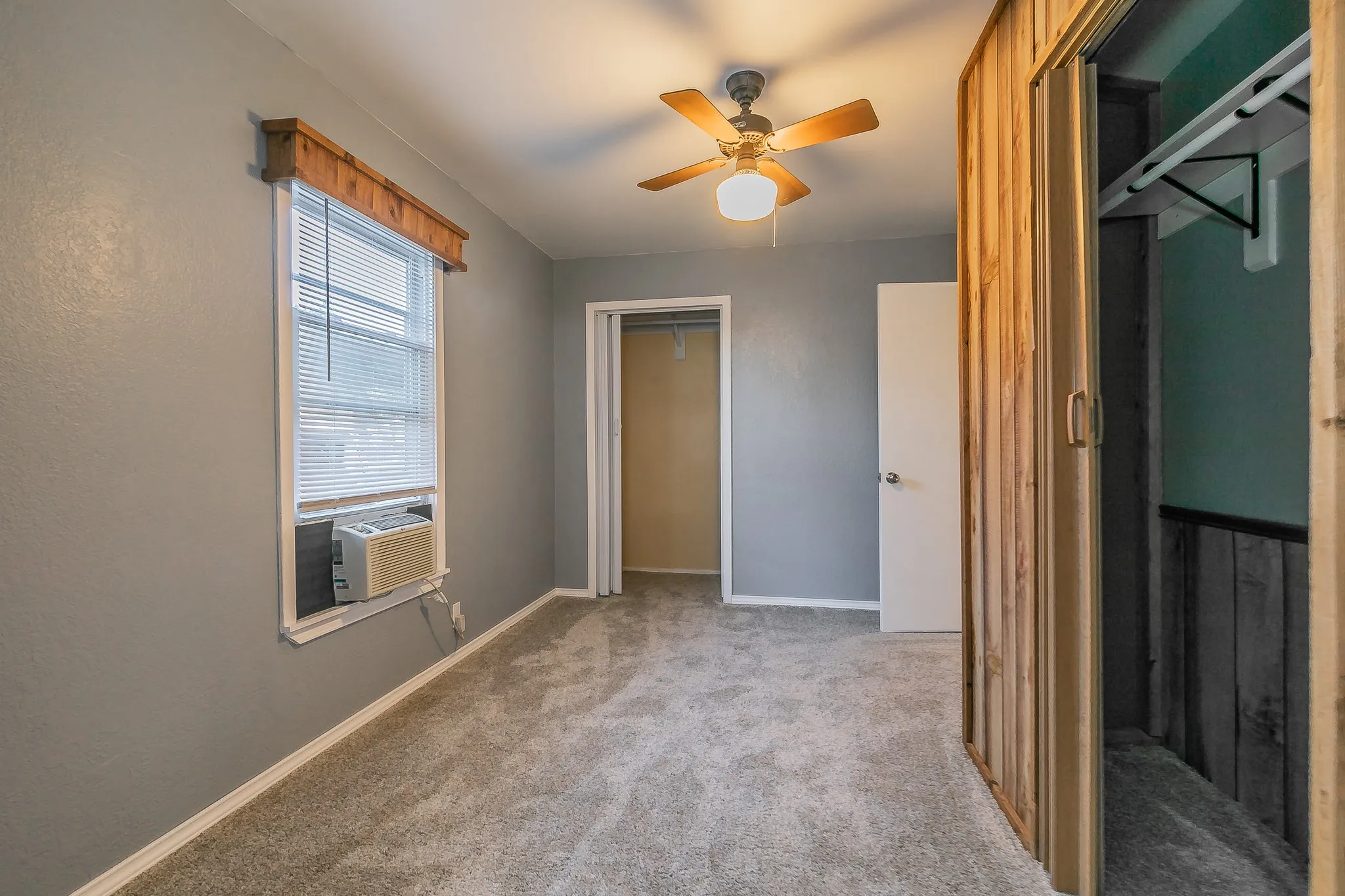 Unfurnished bedroom featuring ceiling fan, cooling unit, light carpet, and a closet