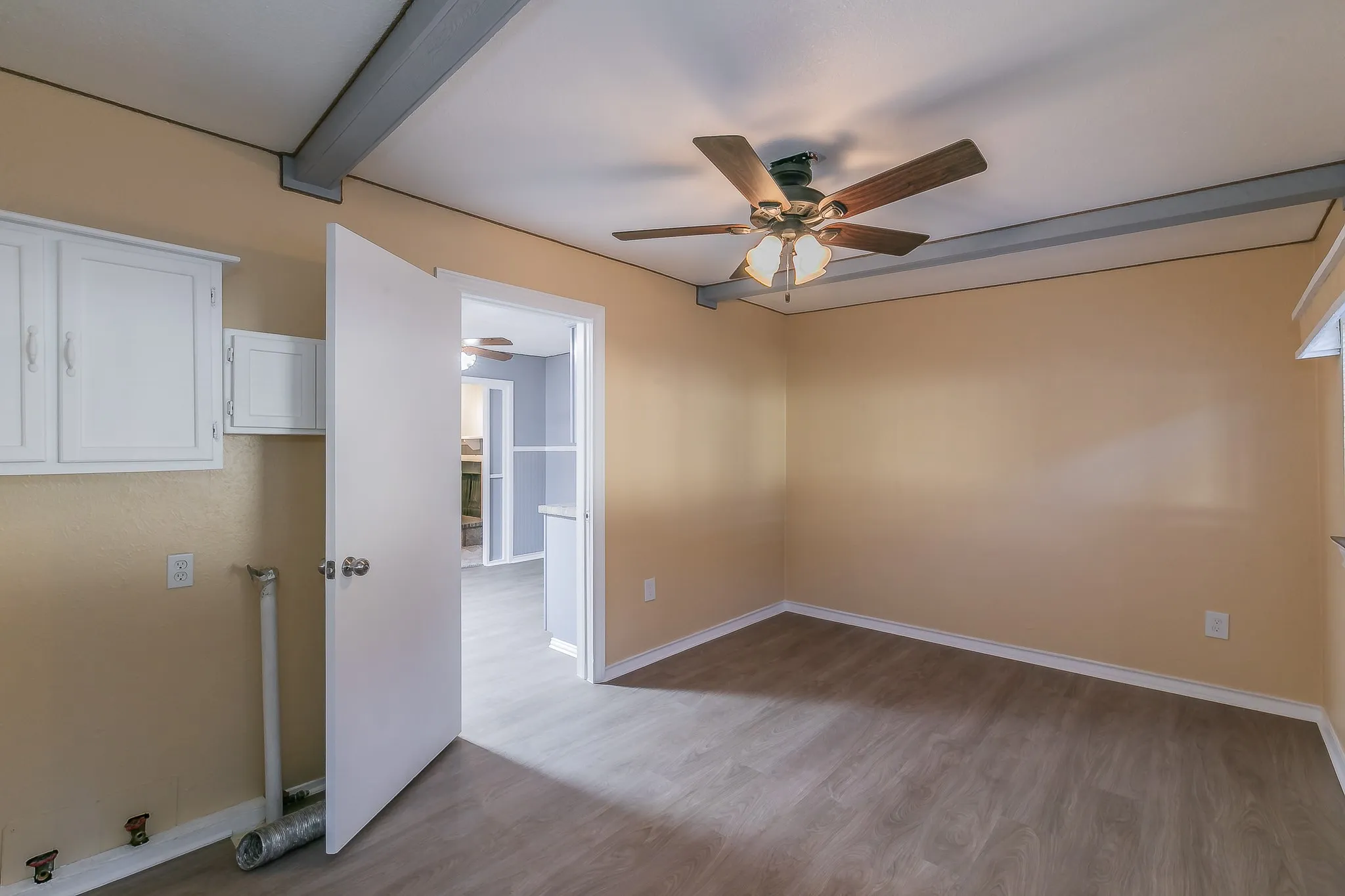 Unfurnished room with ceiling fan, beam ceiling, and light wood-type flooring