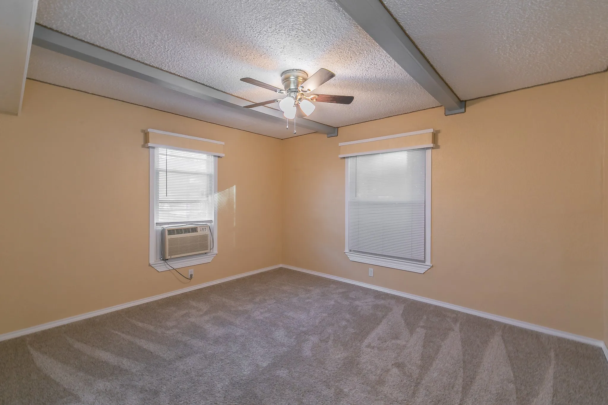 Spare room featuring ceiling fan, beamed ceiling, carpet, and a textured ceiling