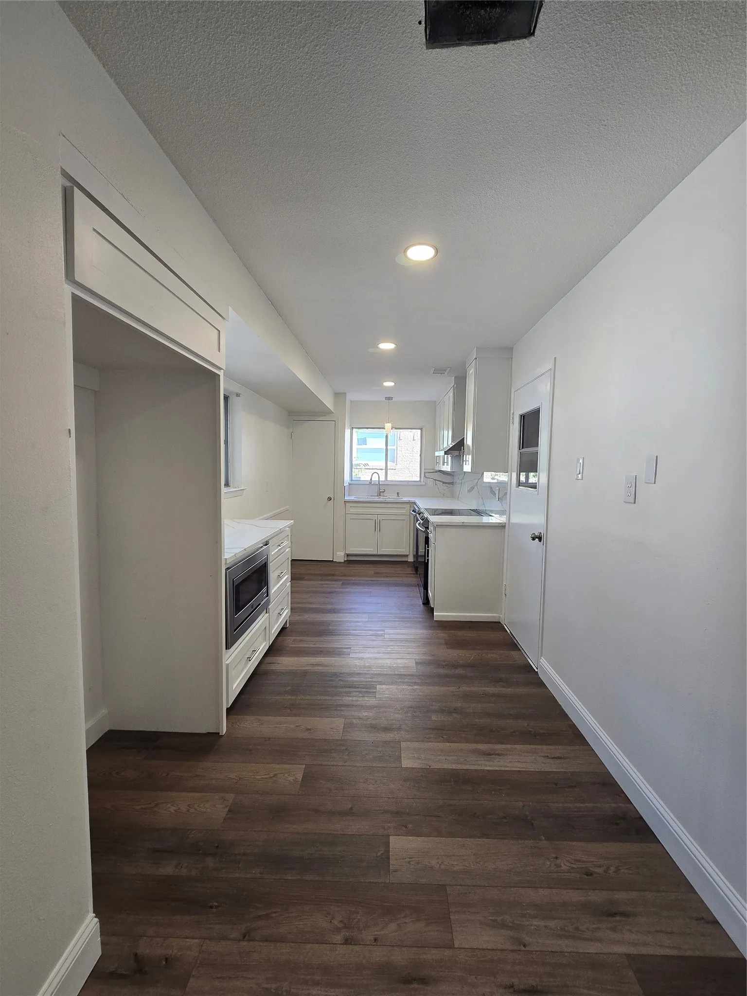 Kitchen featuring wood-finish flooring, white cabinetry, integrated microwave, and recessed lighting