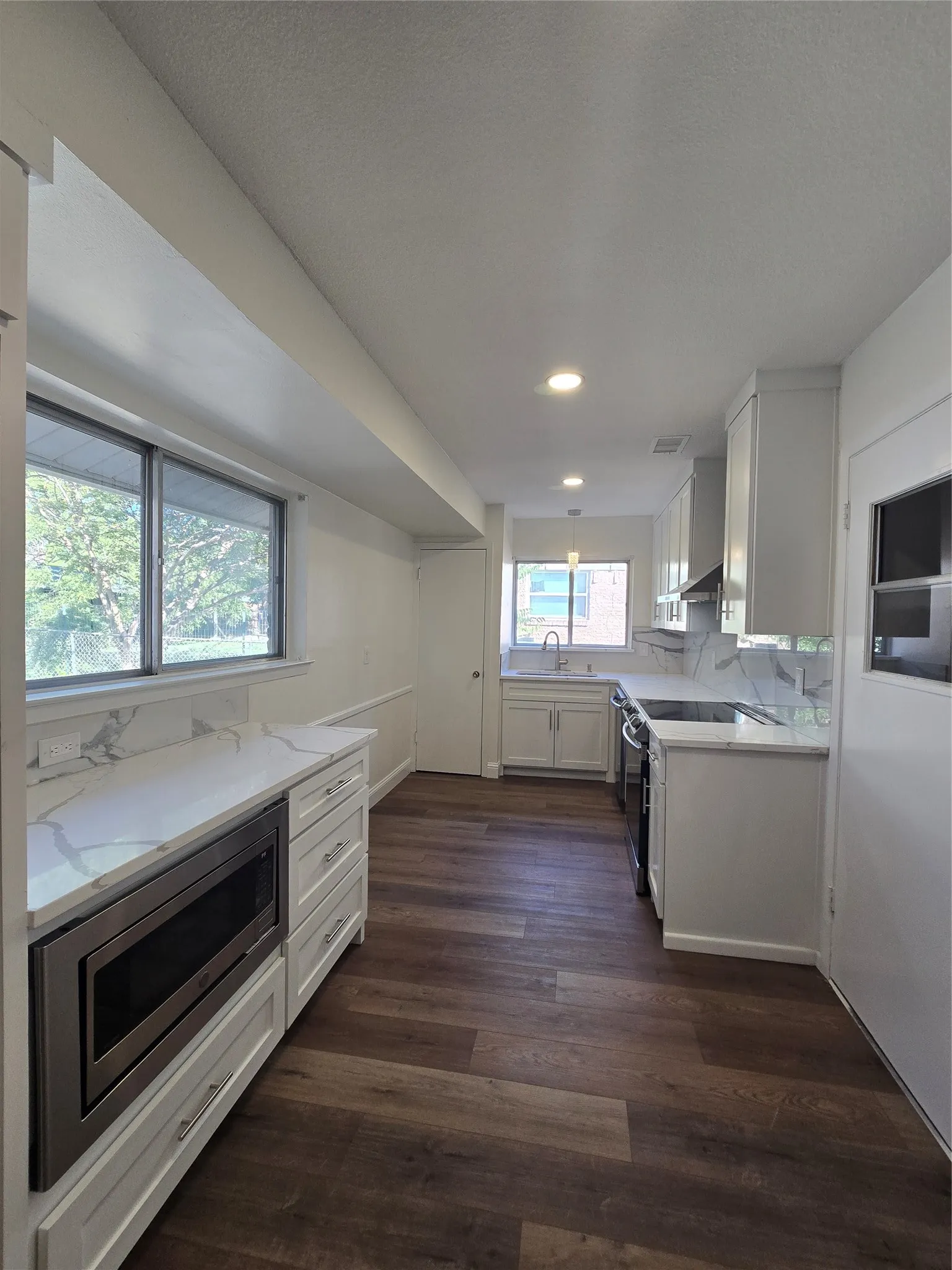 Kitchen featuring white cabinetry, stone-finish countertops, wood-finish flooring, recessed lighting, and a built-in microwave