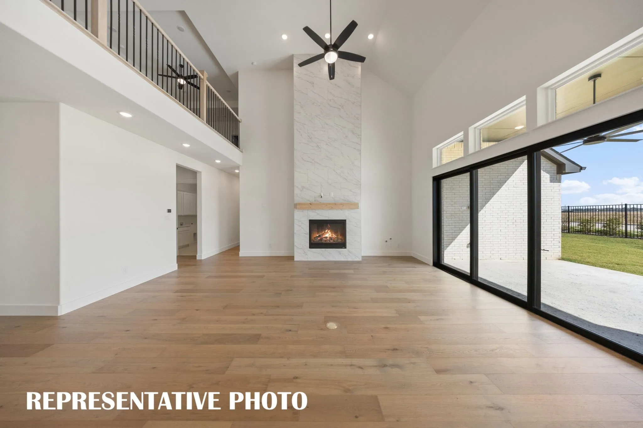 Featuring soaring ceilings, a cozy fire place and full wall slider, this family room is the ideal space for the family to gather.  REPRESENTATIVE PHOTO