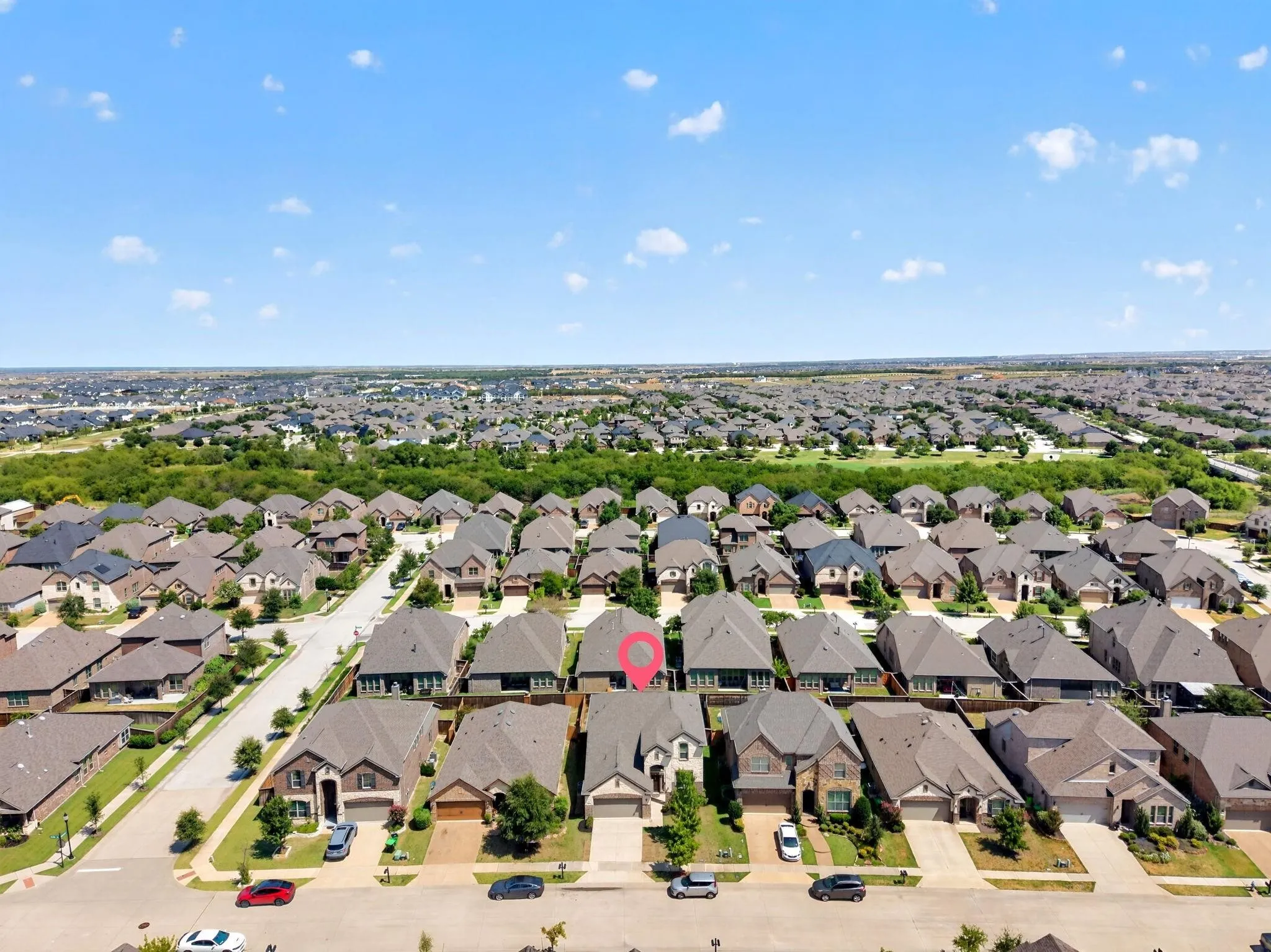 Aerial perspective of residential property featuring a multi-gabled roofline, brick and stone veneer exterior, attached two-car garage, and concrete driveway