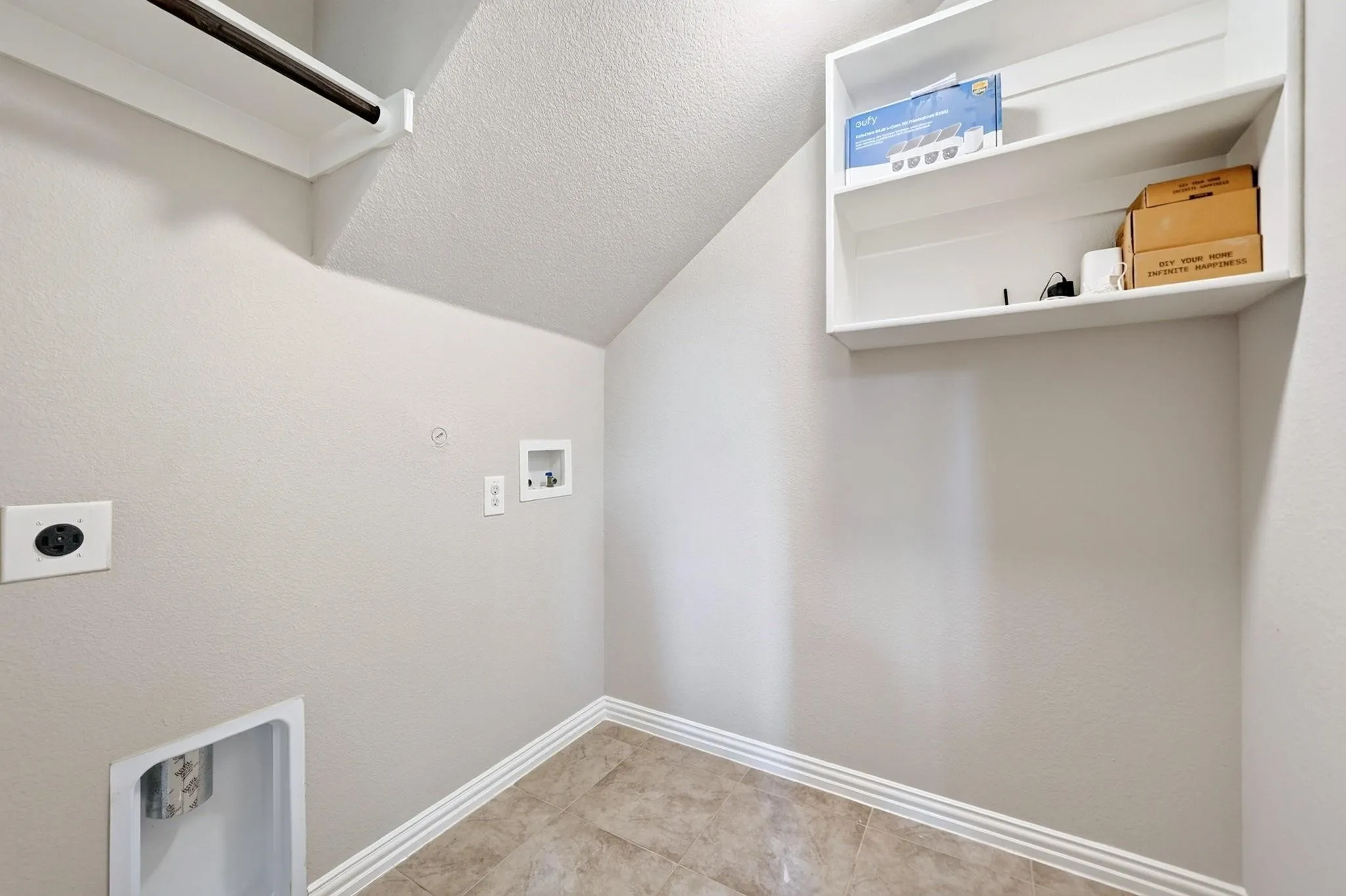 Utility space featuring ceramic tile flooring, built-in white shelving, and dedicated hookups for laundry appliances