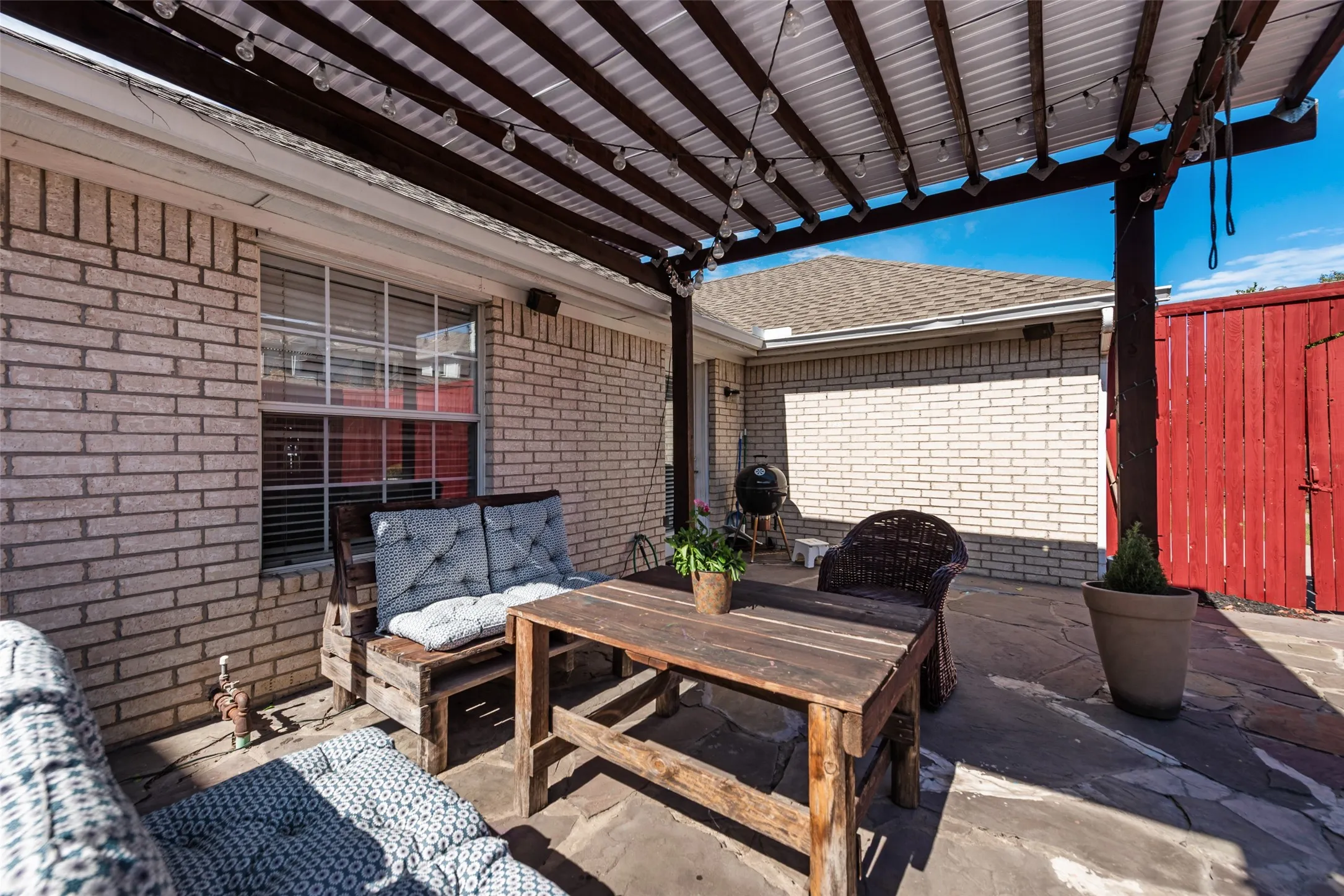 Covered patio featuring a wood pergola, brick exterior siding, and flagstone paving