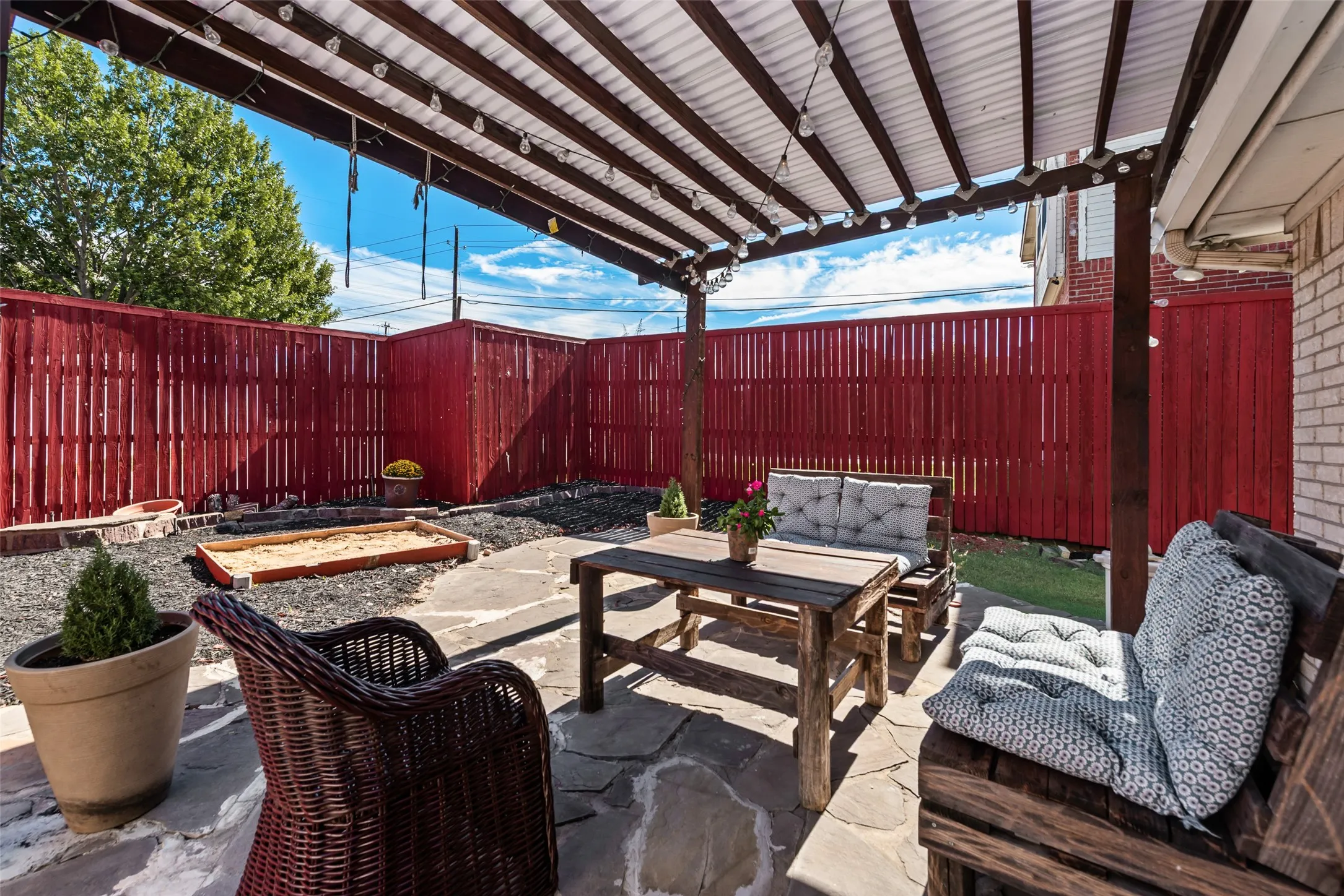 Outdoor living space featuring a flagstone patio, wood-framed pergola, and privacy fencing