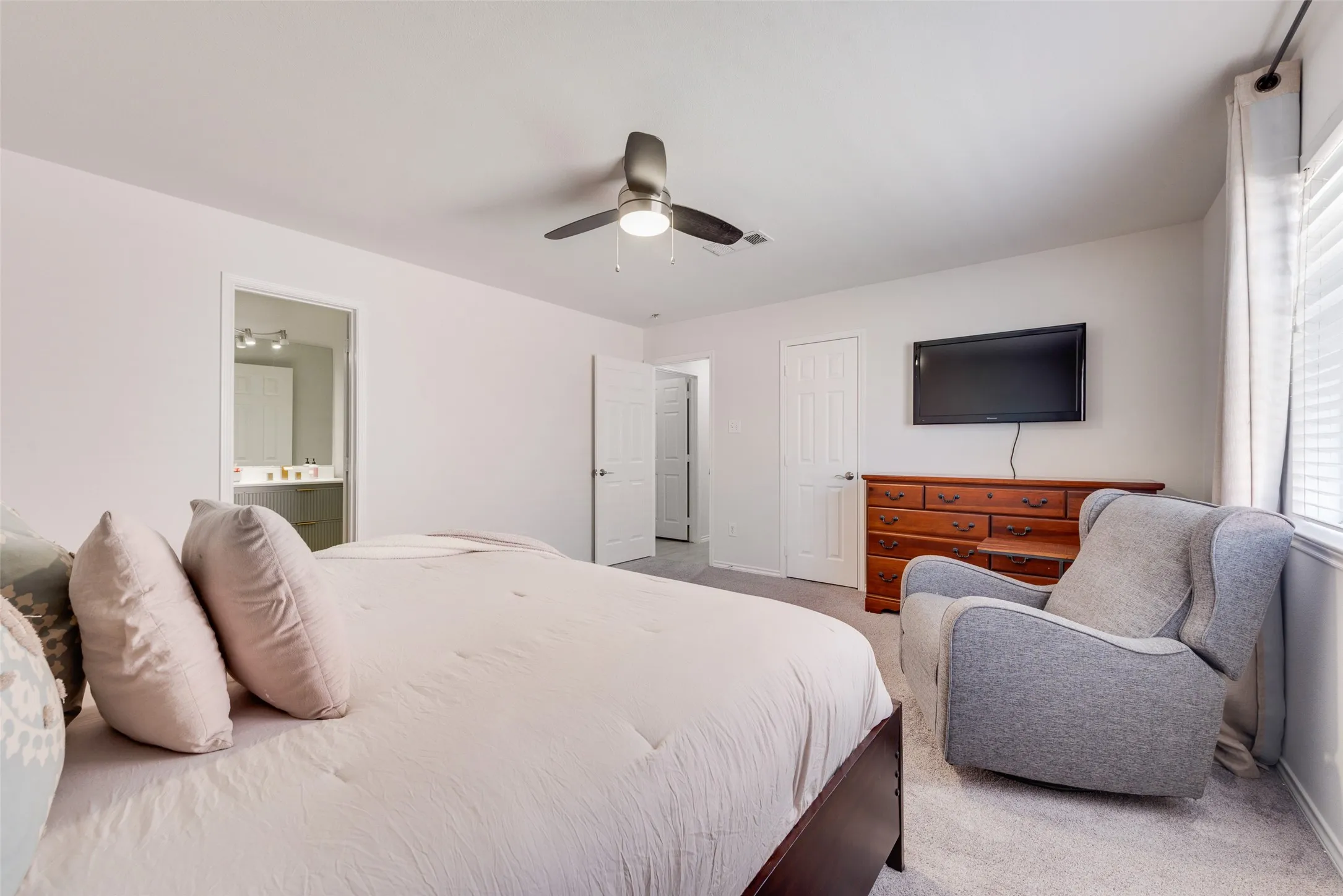 Interior room featuring neutral wall tones, wall-to-wall carpeting, a multi-blade ceiling fan with an integrated light fixture, and two interior doors with paneled detailing