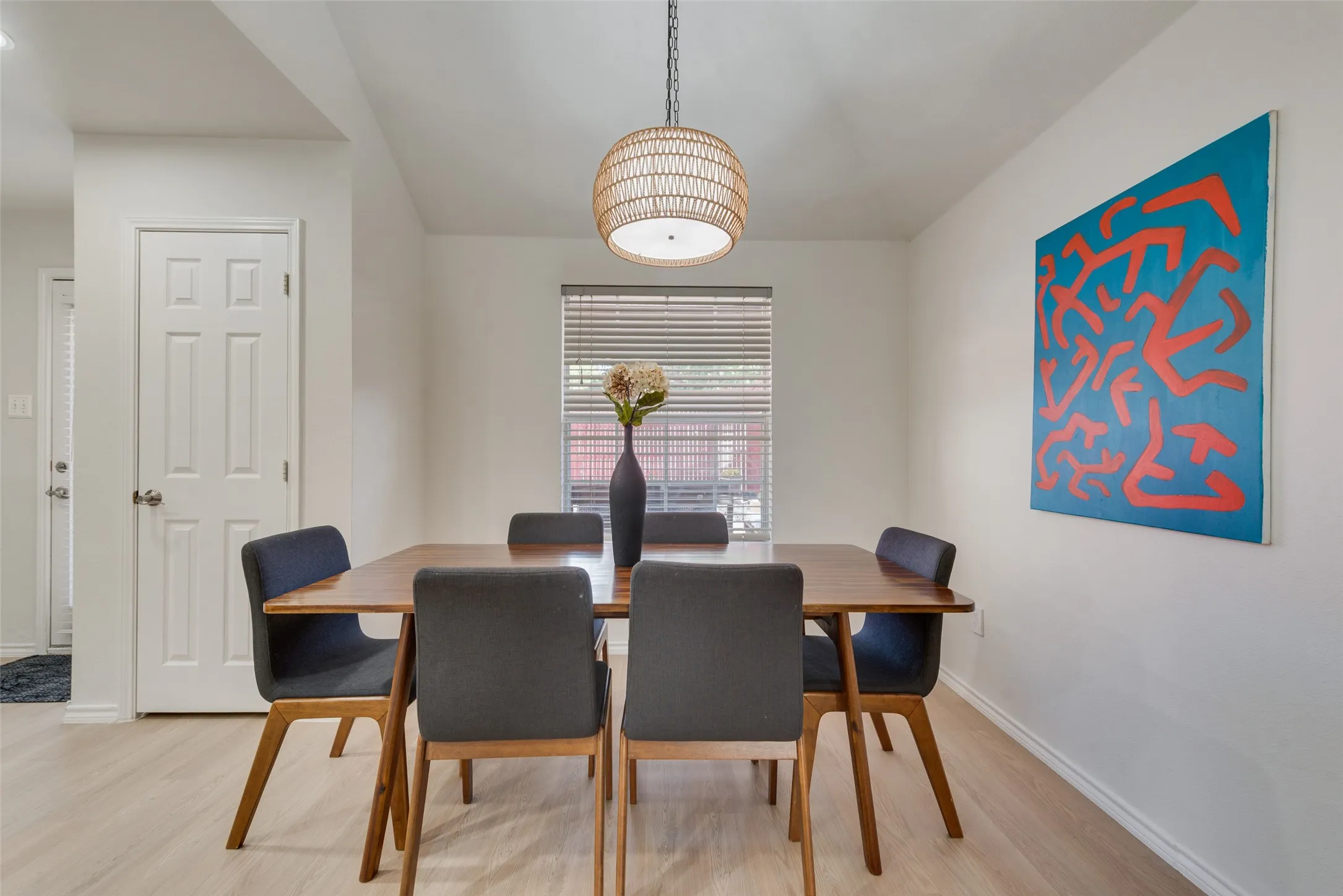 Woven basket-style pendant light fixture, wood-finish flooring, and horizontal window blinds