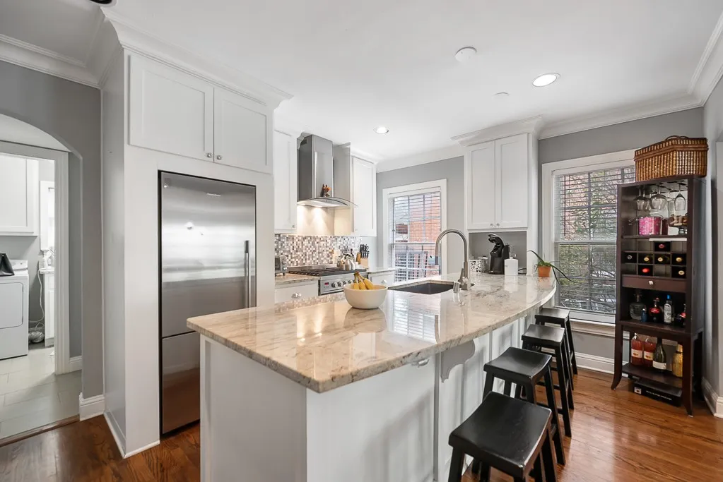 Kitchen featuring white cabinetry, stone countertops, a stainless steel refrigerator, patterned tile backsplash, and wood-finish flooring