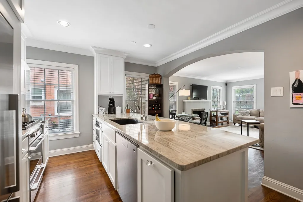 Kitchen featuring white cabinetry, stone countertops, an integrated sink, stainless steel appliances, and wood-finish flooring