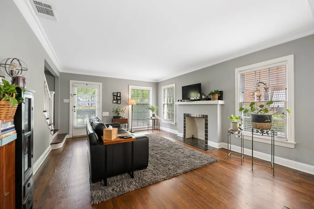 Living area featuring dark wood-finish flooring, crown molding, a fireplace with a tile surround and mantel, and multiple windows