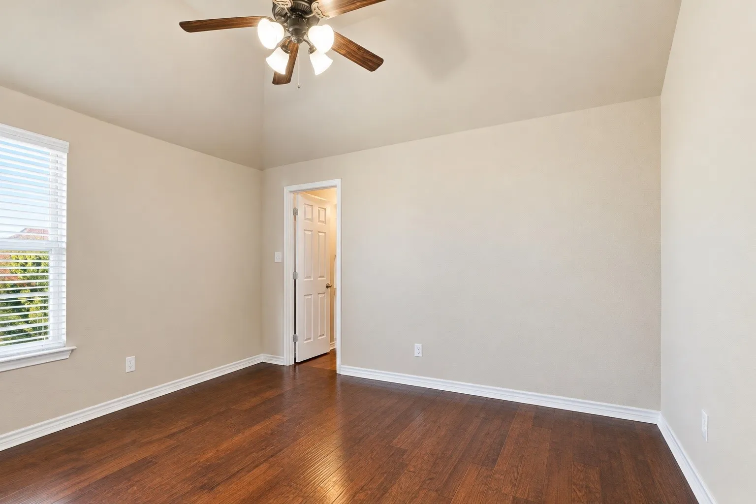 Rich wood details and hardwood flooring add depth, charm, and sophistication to this spacious bedroom.