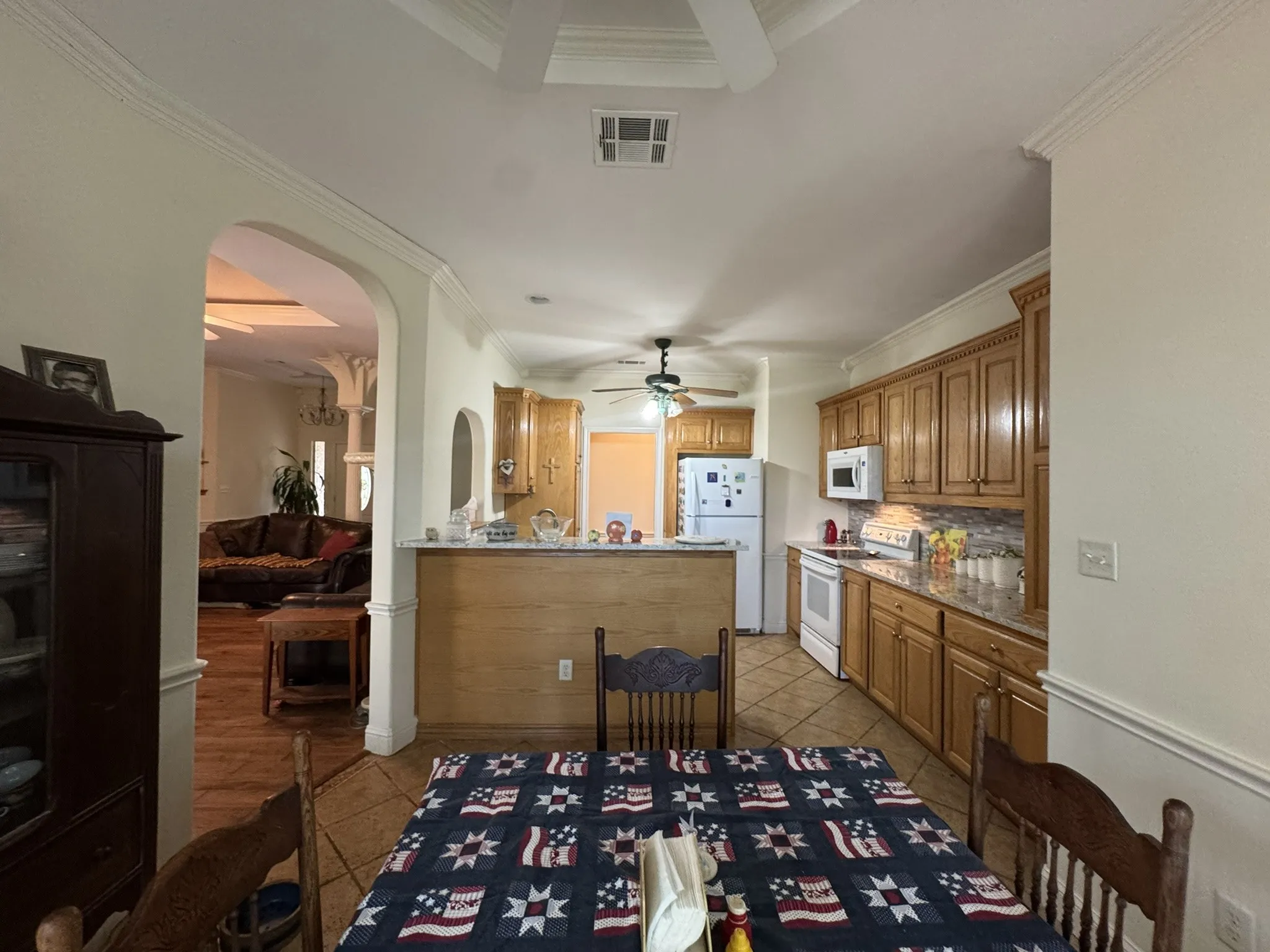 Kitchen featuring wood cabinetry, stone-finish countertops, tile flooring, and a breakfast bar with built-in millwork
