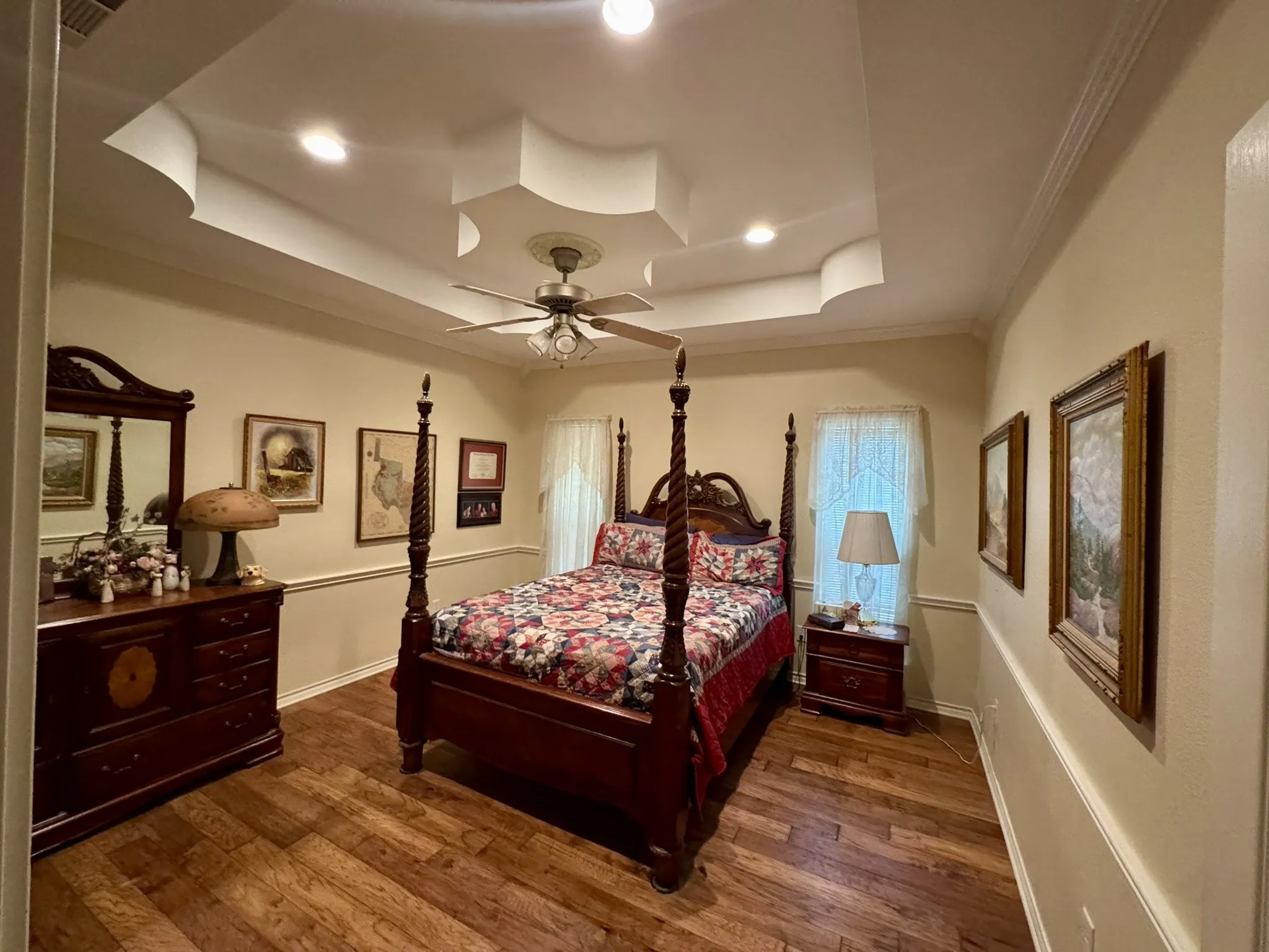 Tray ceiling with recessed lighting, wood-finish flooring, and chair rail molding