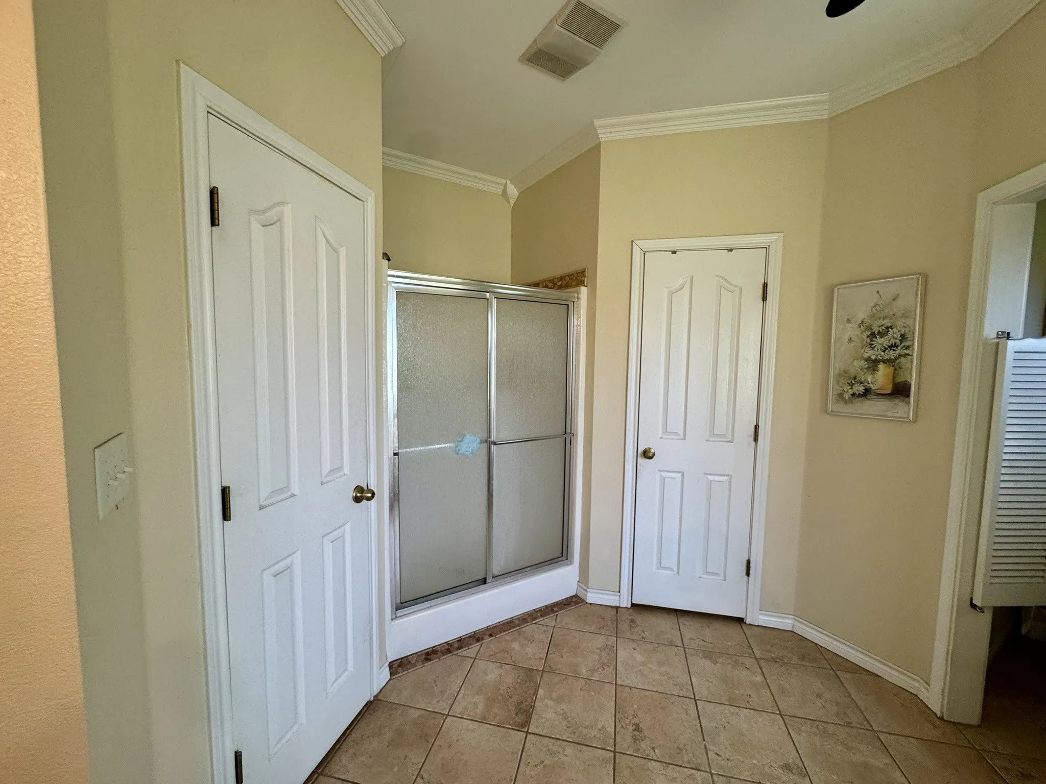 Ceramic tile flooring, crown molding, and a walk-in shower with a metal frame enclosure