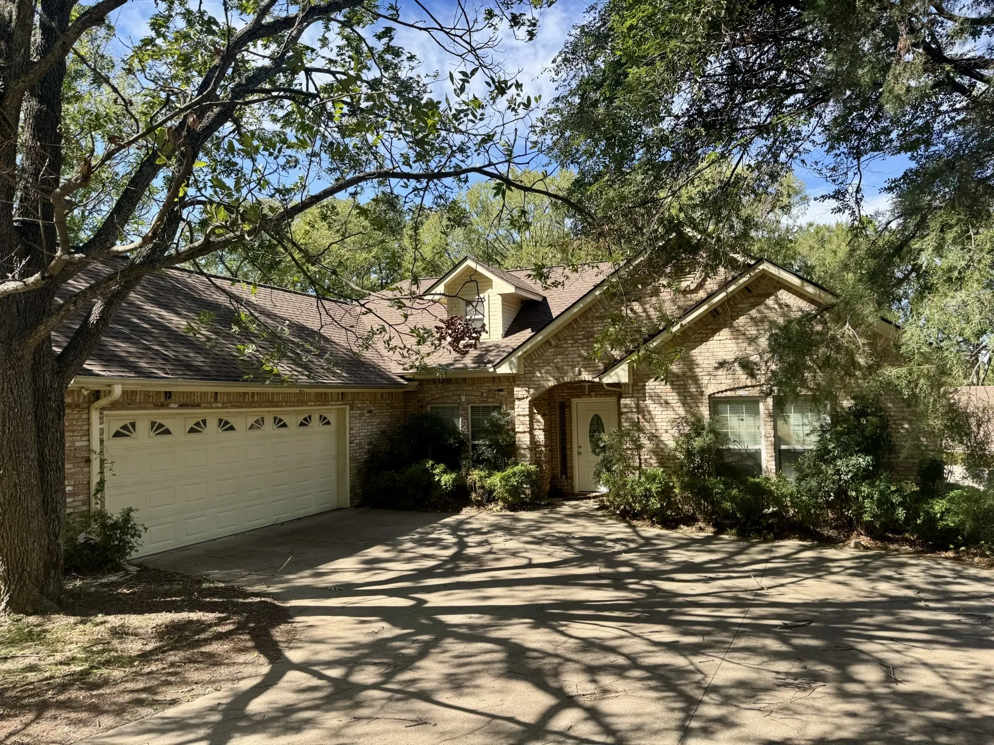 Brick exterior featuring a gabled roofline, arched entryway, multi-paned windows, and an attached two-car garage