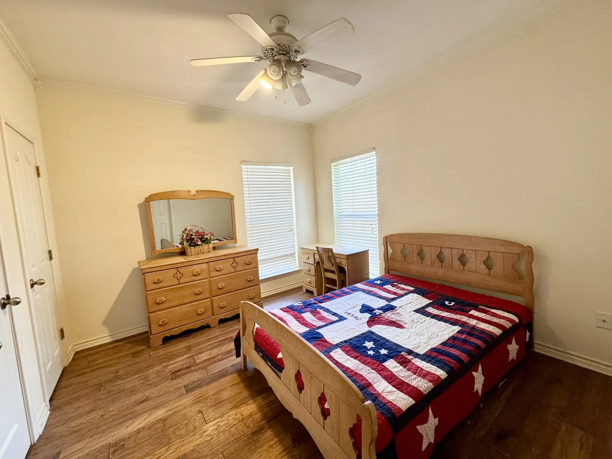 Wood-finish flooring, ceiling fan with integrated lighting, and dual windows with horizontal blinds