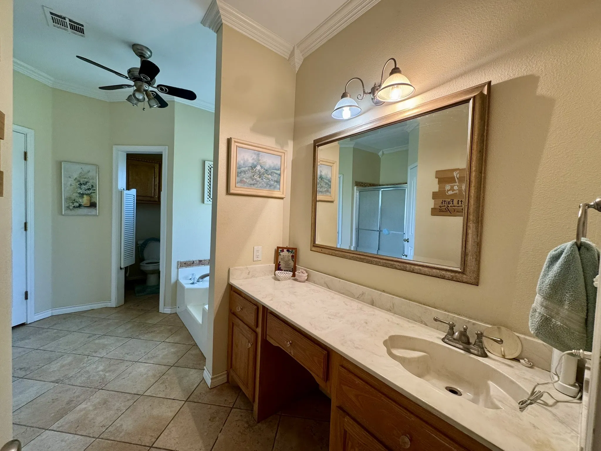 Bathroom featuring a dual-basin vanity with a stone countertop, crown molding, tile flooring, and an integrated bathtub