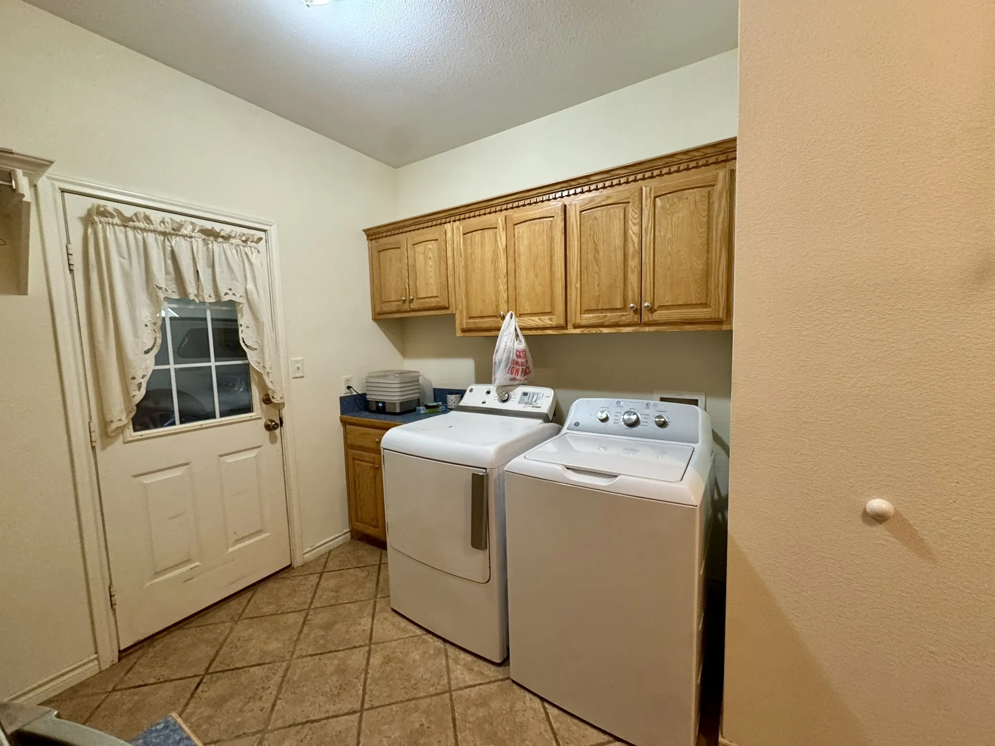 Utility area featuring wood-finish cabinetry, tile flooring, and exterior access door
