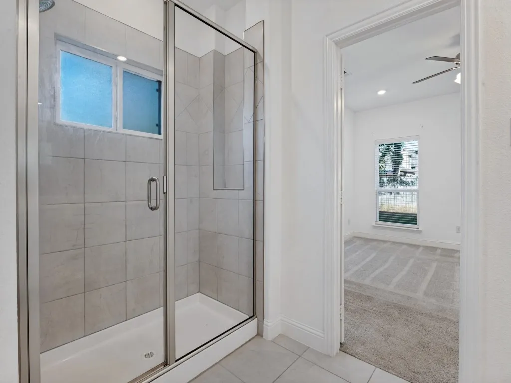 Spacious primary shower with tile surround and a glass enclosure.