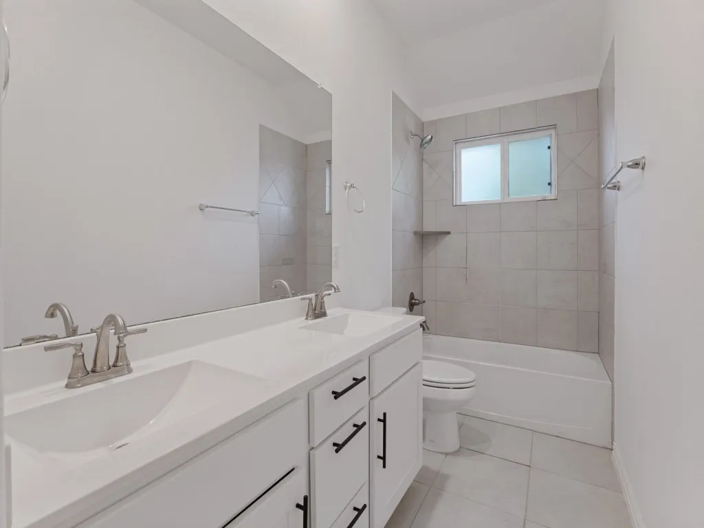 Additional bathroom featuring dual sinks and a tub and shower combination