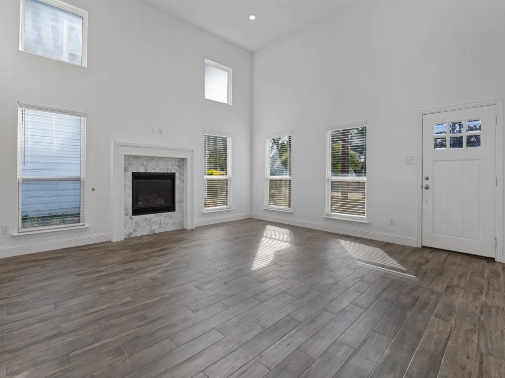 Soaring ceilings, abundant natural light, and a welcoming fireplace highlight the spacious living room
