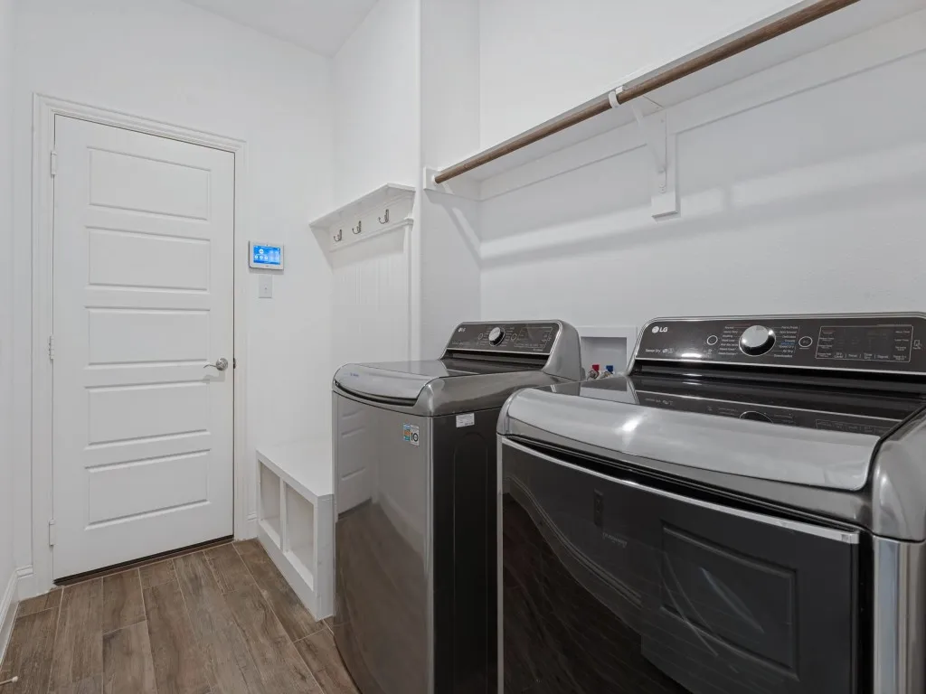 Dedicated laundry room with overhead shelving and space for a full-size washer and dryer