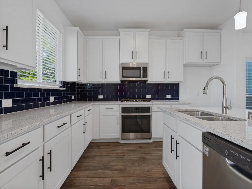 Beautiful kitchen featuring white cabinetry, granite countertops, stainless steel appliances, and a large island