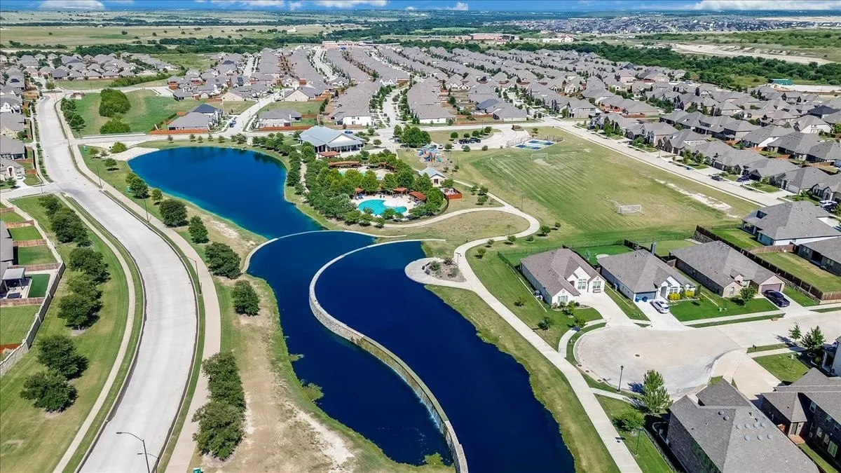 Aerial view of community features including a central pond, paved walking trails, and a recreational pool facility