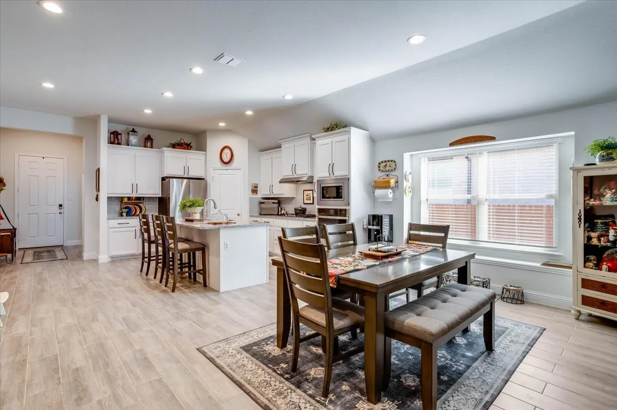Open-concept kitchen featuring white cabinetry, stone-surface countertops, recessed lighting, and wood-finish flooring