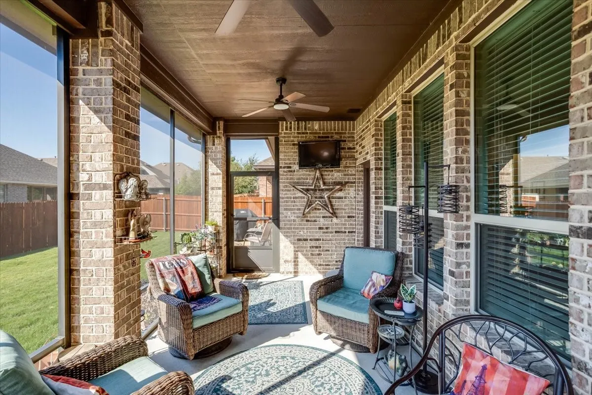 Screened-in patio featuring brick exterior walls, a covered ceiling with dual overhead fans, and large pane windows