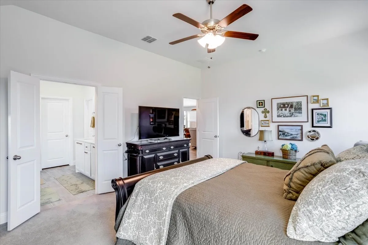Vaulted ceilings, neutral wall finishes, and a brushed nickel ceiling fan with integrated light fixture