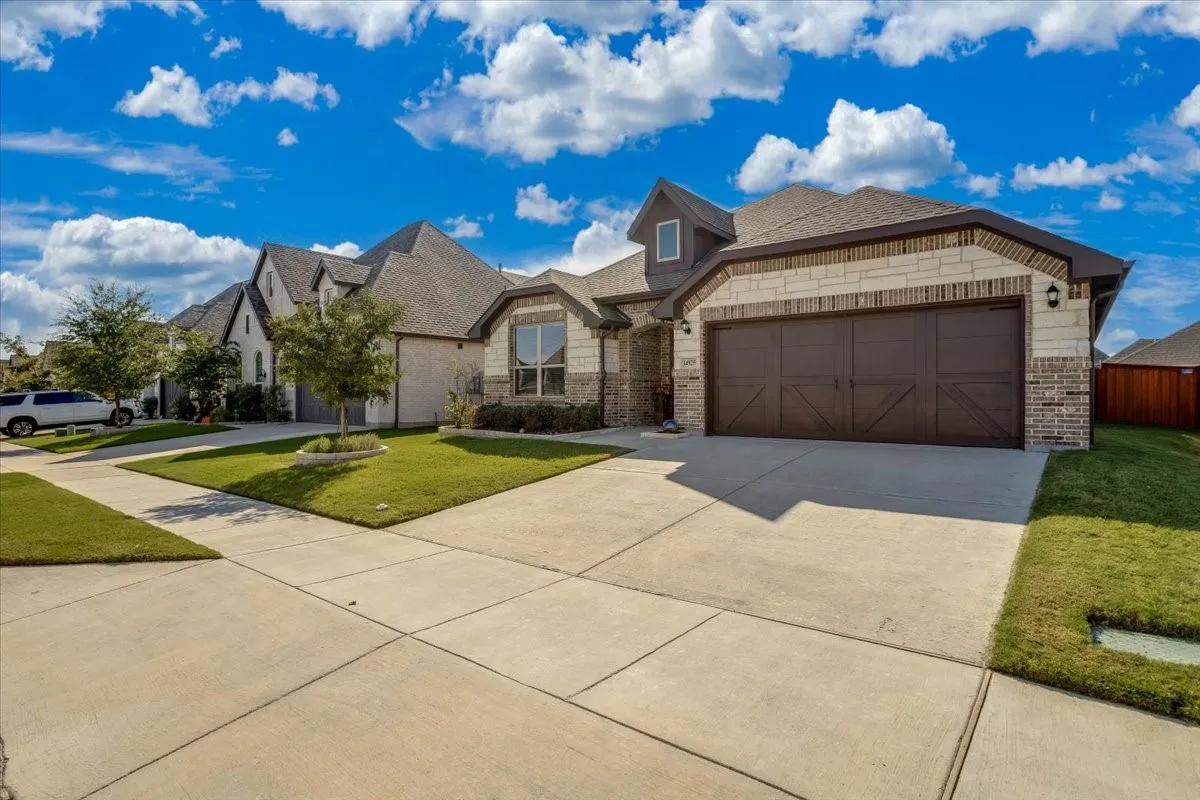 Exterior featuring a combination of stone and brick masonry, a multi-gabled roofline, an attached two-car garage with carriage-style doors, and a concrete driveway