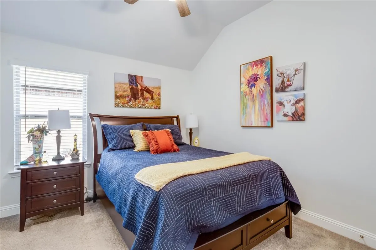 Vaulted ceilings, neutral carpeting, and a ceiling fan with integrated lighting