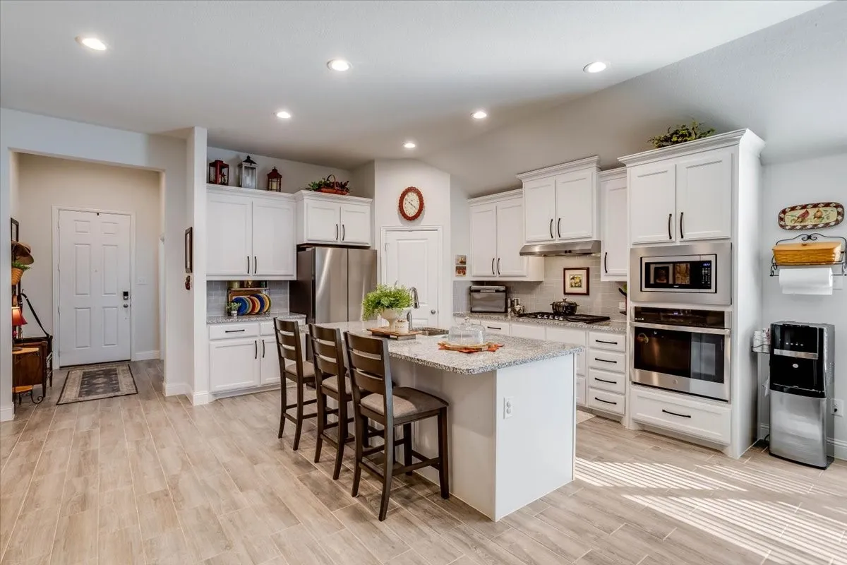 Kitchen featuring white shaker-style cabinetry, stone-finish countertops, stainless steel wall-mounted oven and microwave, recessed lighting, and wood-finish flooring