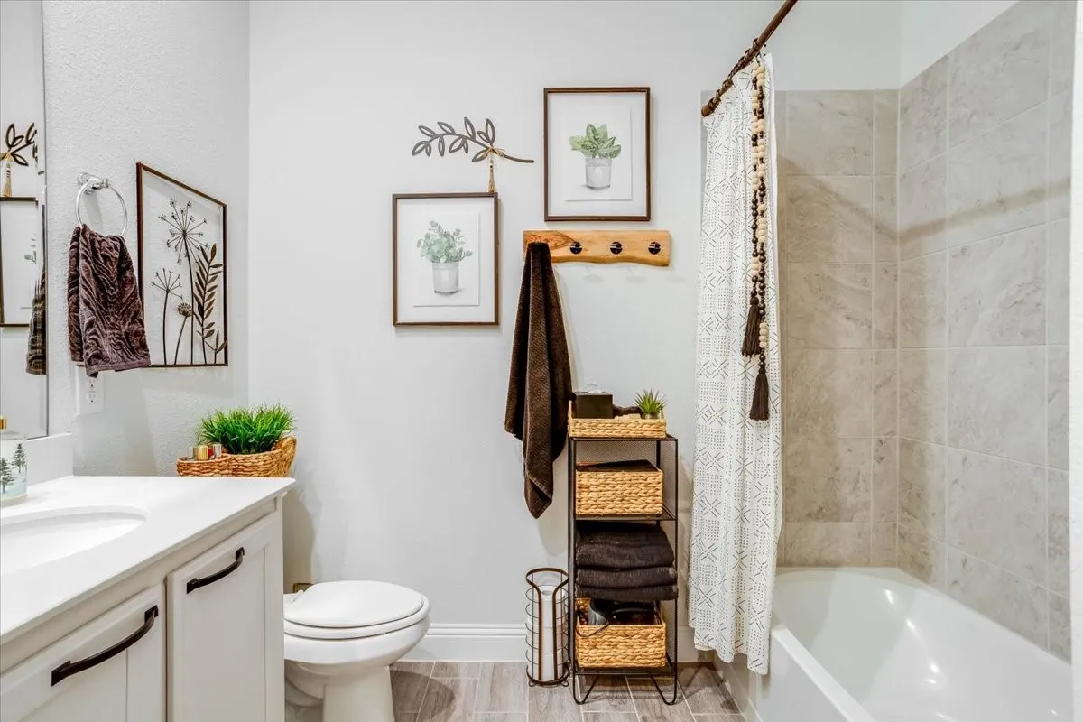 Bathroom featuring a vanity with a white countertop and dark hardware, porcelain-finish tub surround, and tile flooring