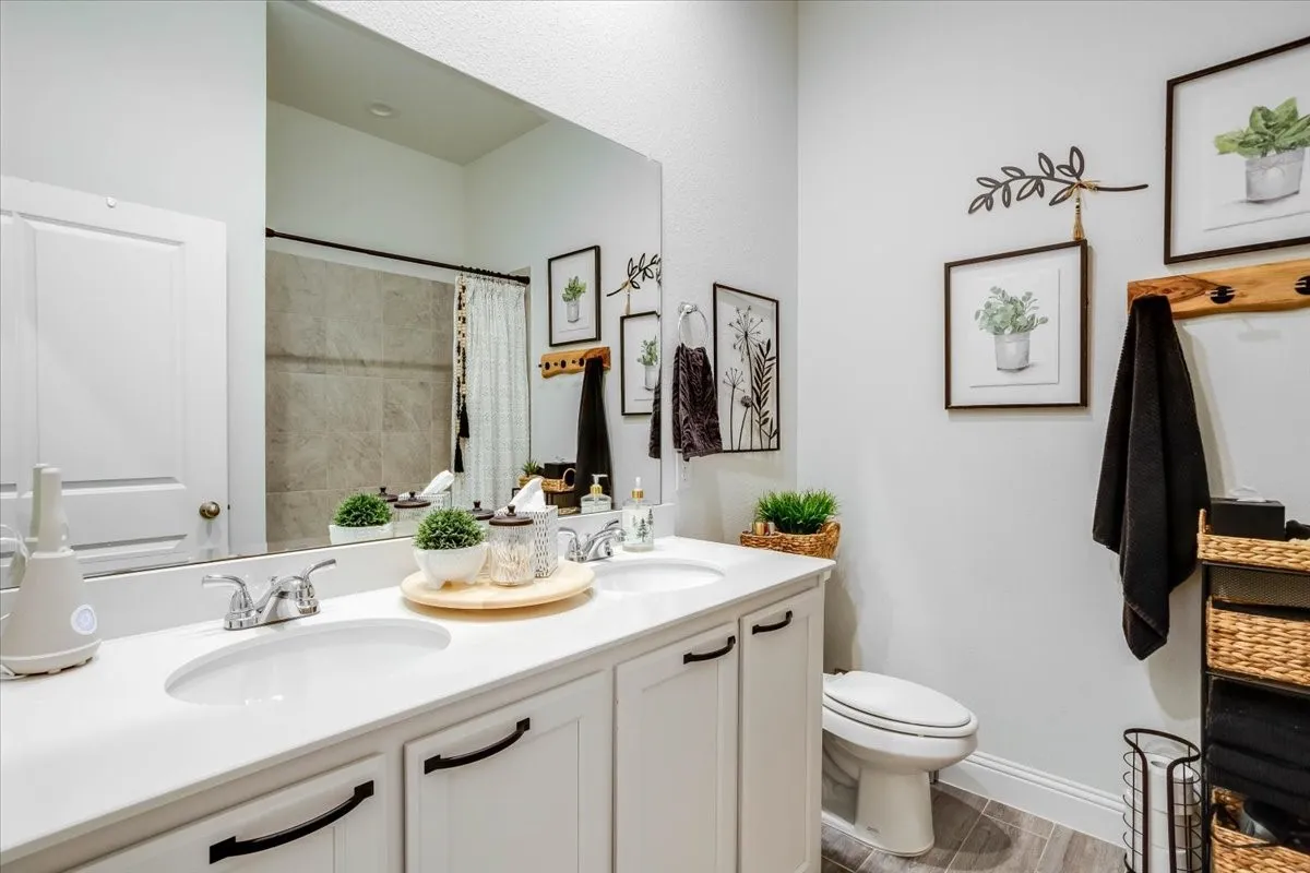 Bathroom featuring a dual-sink vanity with white countertops, undermount sinks, matte black hardware, a full-width mirror, and a tile-surround shower