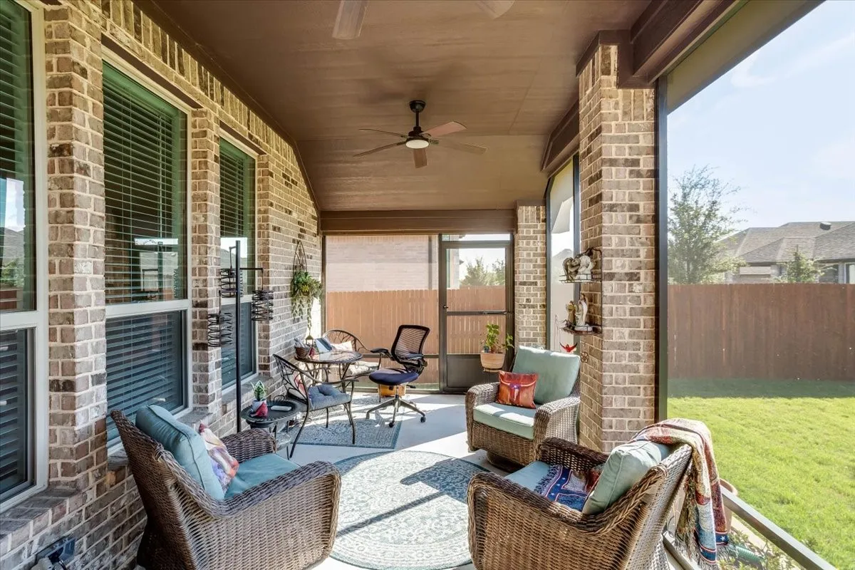 Covered patio featuring brick masonry, a screen enclosure, and a ceiling fan