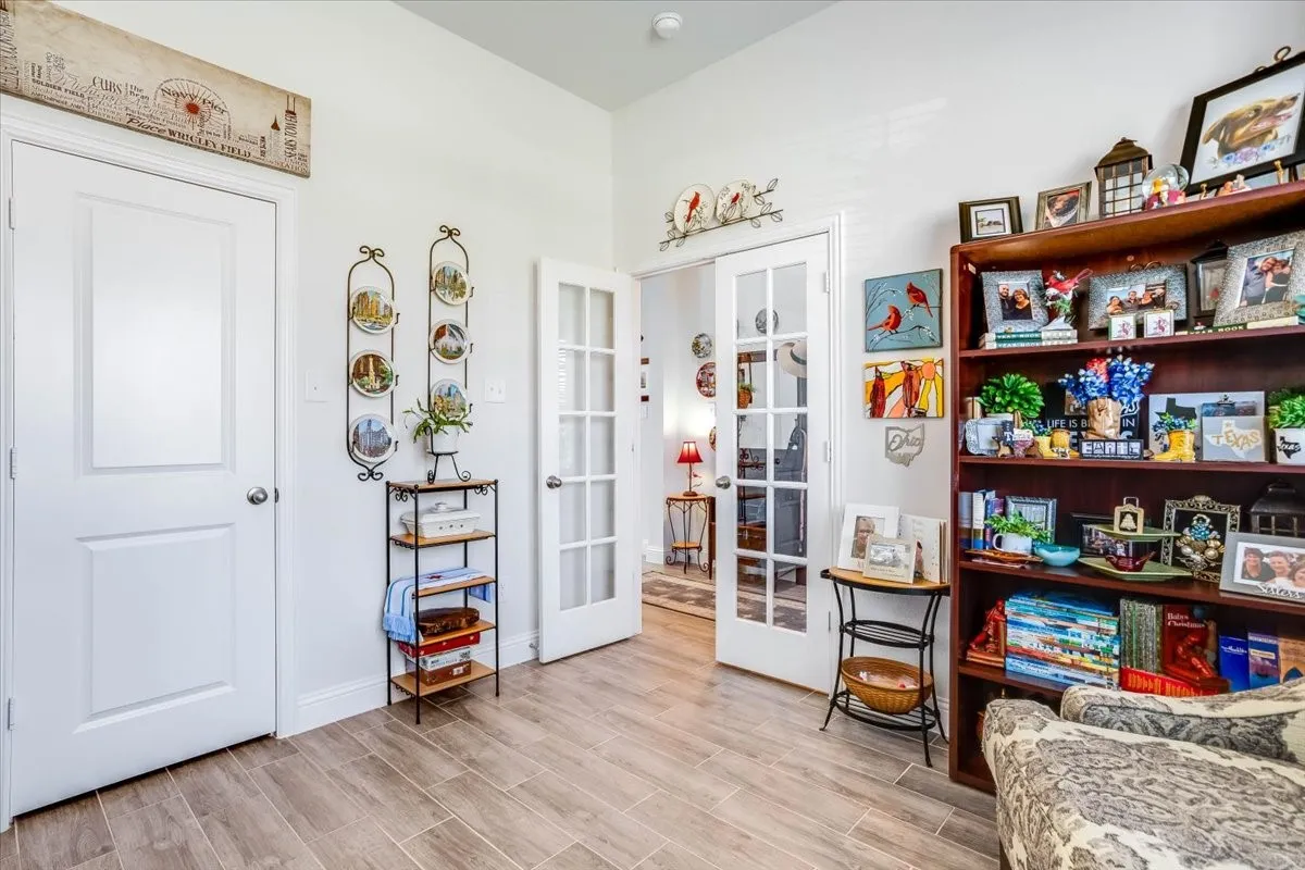 Wood-finish tile flooring, white shaker-style interior doors, and glass-paneled French doors featuring multi-lite design