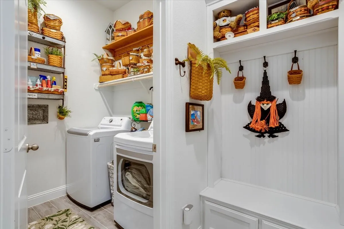 Utility space featuring built-in wooden shelving, a custom mudroom bench with beadboard wainscoting, integrated overhead storage cabinets, and tile flooring