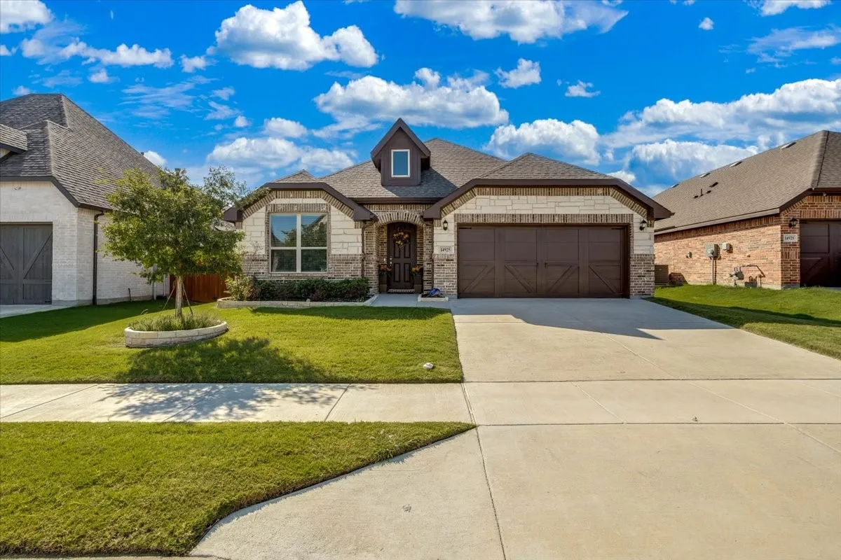 Exterior featuring a brick and stone facade, an arched entryway, a multi-gabled roofline, and a multi-car garage with decorative paneling