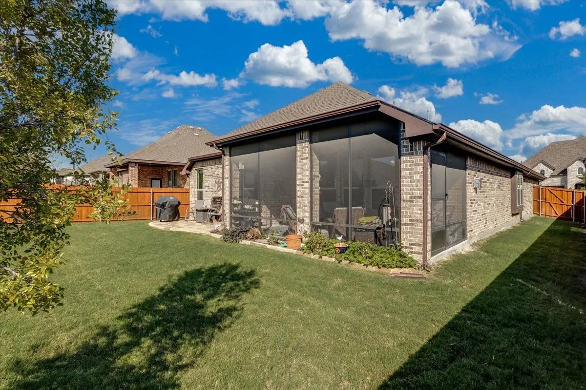 Brick exterior, screened-in patio, and fenced backyard with mature landscaping