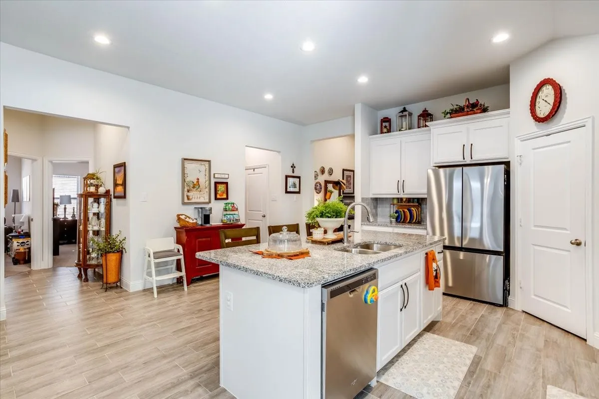 Kitchen featuring white cabinetry, stone-surface countertops, wood-finish flooring, recessed lighting, and stainless steel appliances