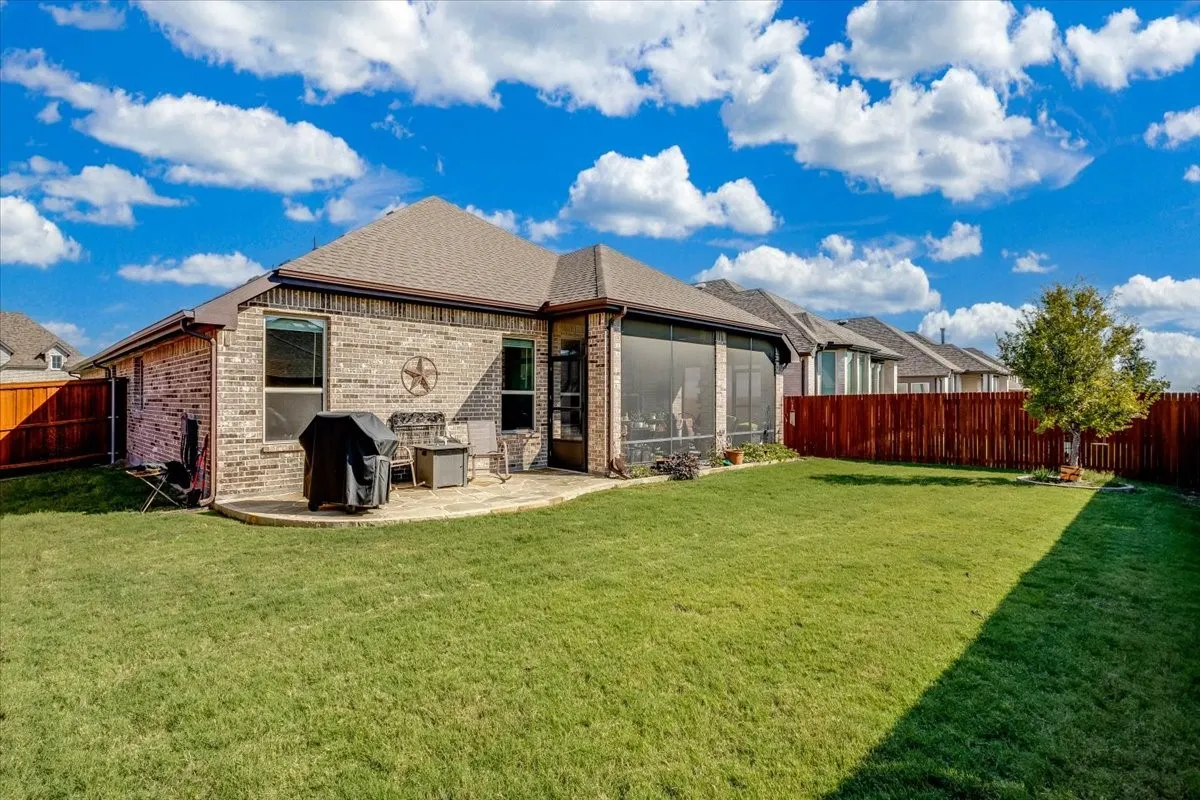 Brick exterior, screened-in patio, stone-paved rear landing, and wood privacy fencing